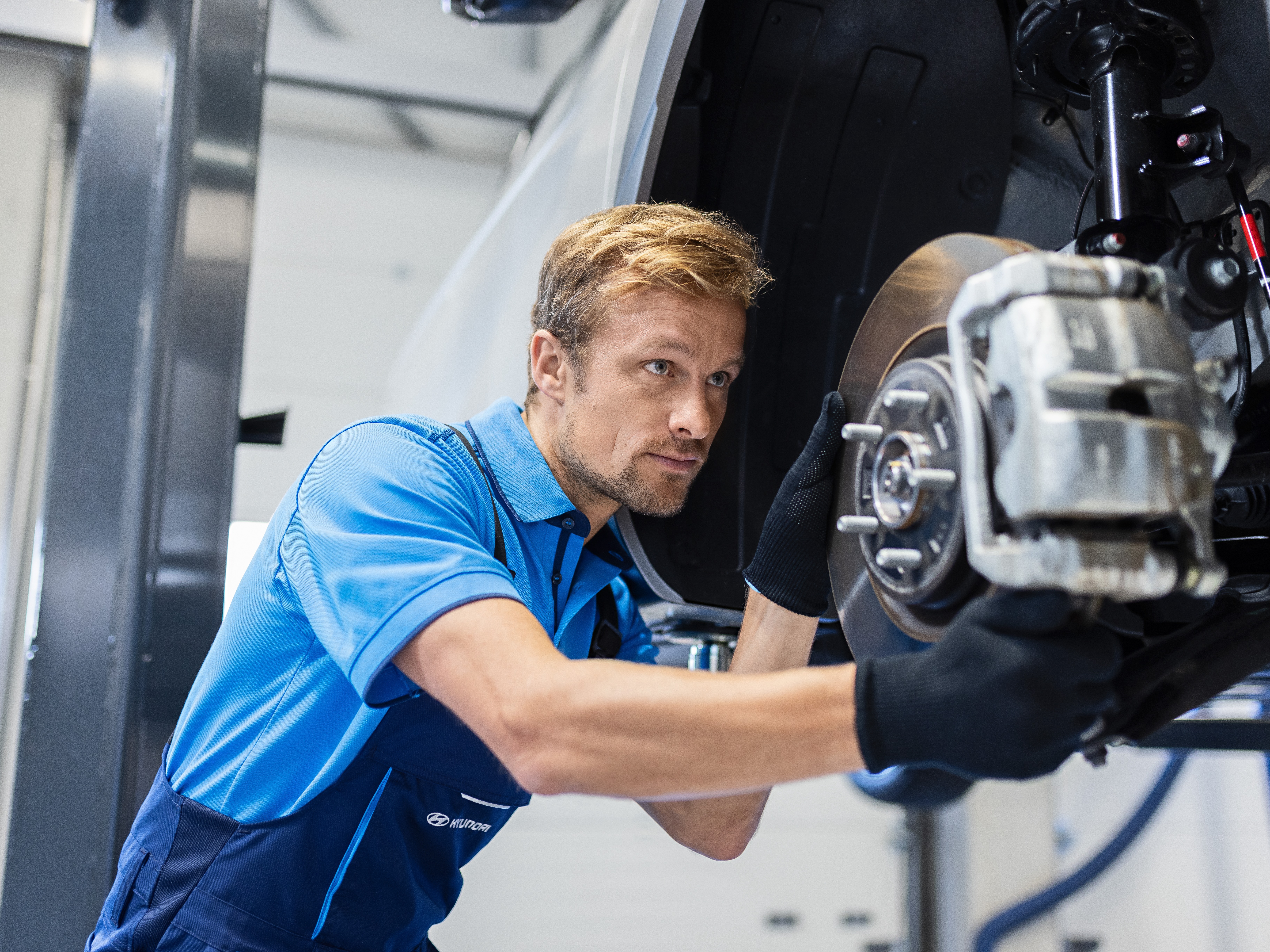 Technik během kontroly brzdového systému vozidla v servisní dílně.
